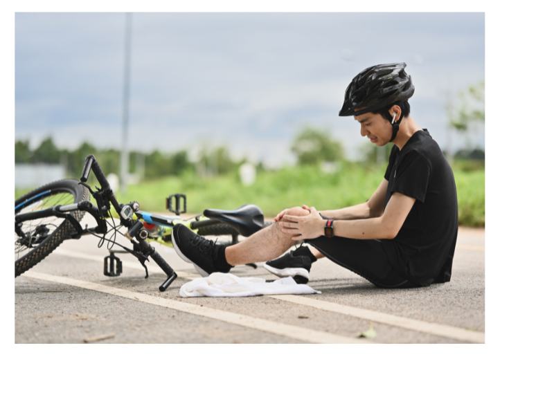 Jugendlicher sitzt auf dem Boden, hält sich das Knie nach einem Sturz mit dem Fahrrad