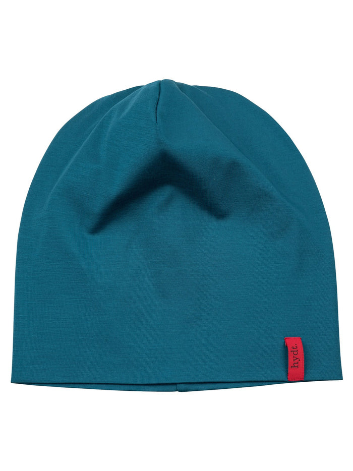  Petrolblaue Beanie für Damen und Herren bei Haarausfall, flach liegend fotografiert, zeigt den feinen Stoff und das rote hydt. Logo