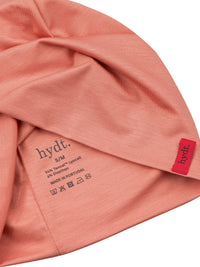 Detailaufnahme der Innenseite der korallenroten hydt. Mütze: Gedruckte Materiallabel, Made in Portugal und Pflegehinweisen.